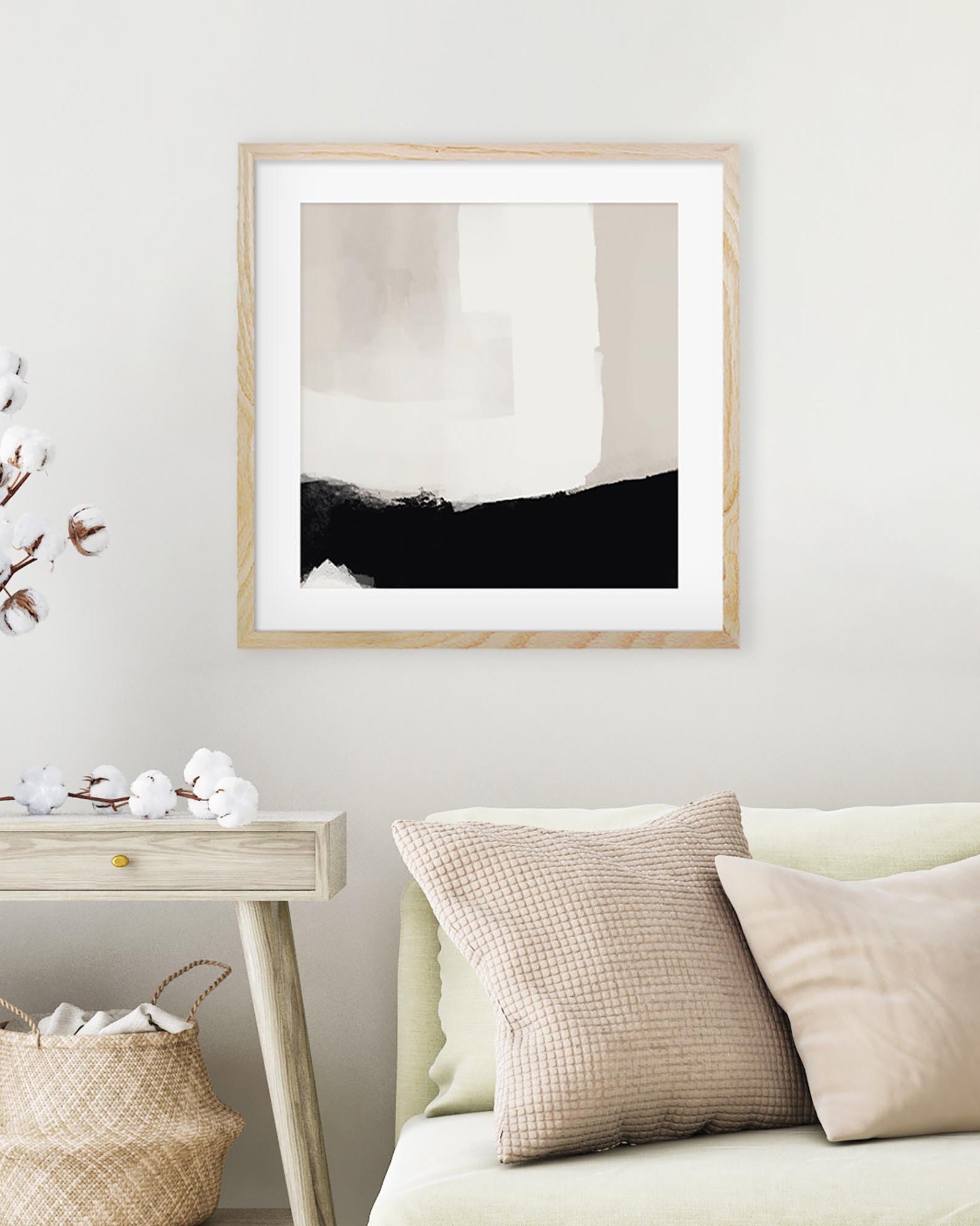 Framed abstract art piece on a wall above a sofa with decorative pillows and baskets.