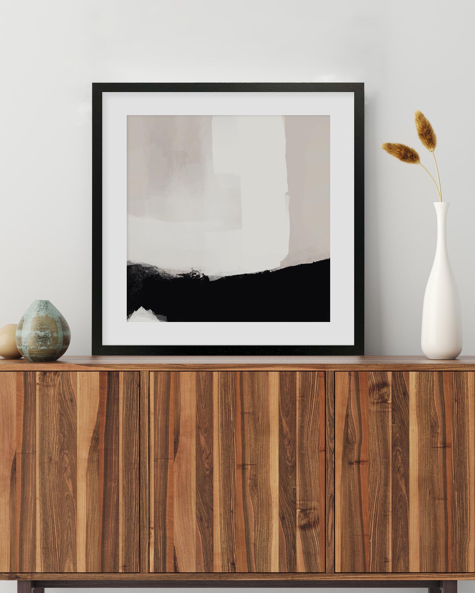 Framed abstract art piece on a wooden sideboard with decorative items.