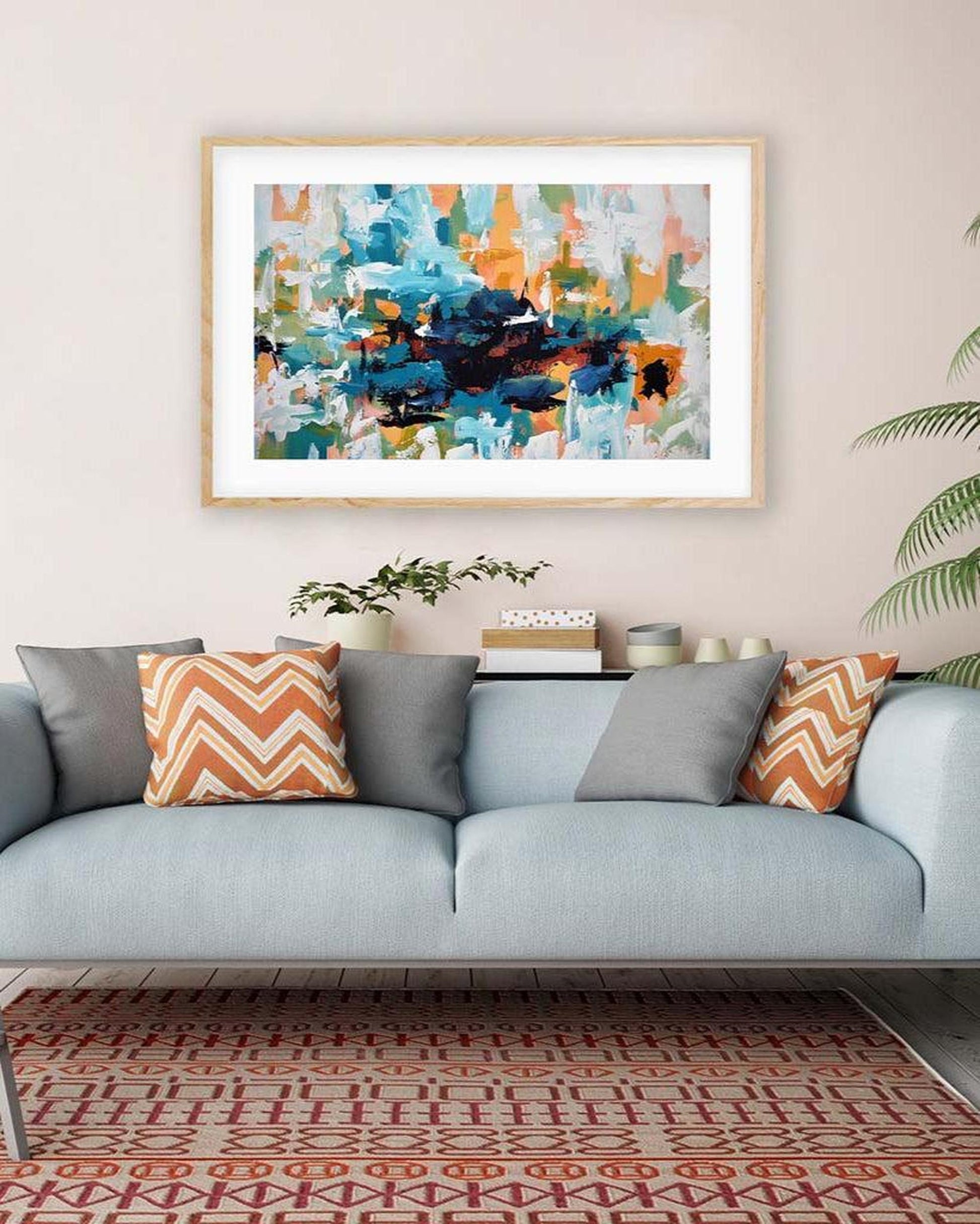 Framed abstract art above a sofa with decorative pillows in a living room setting.
