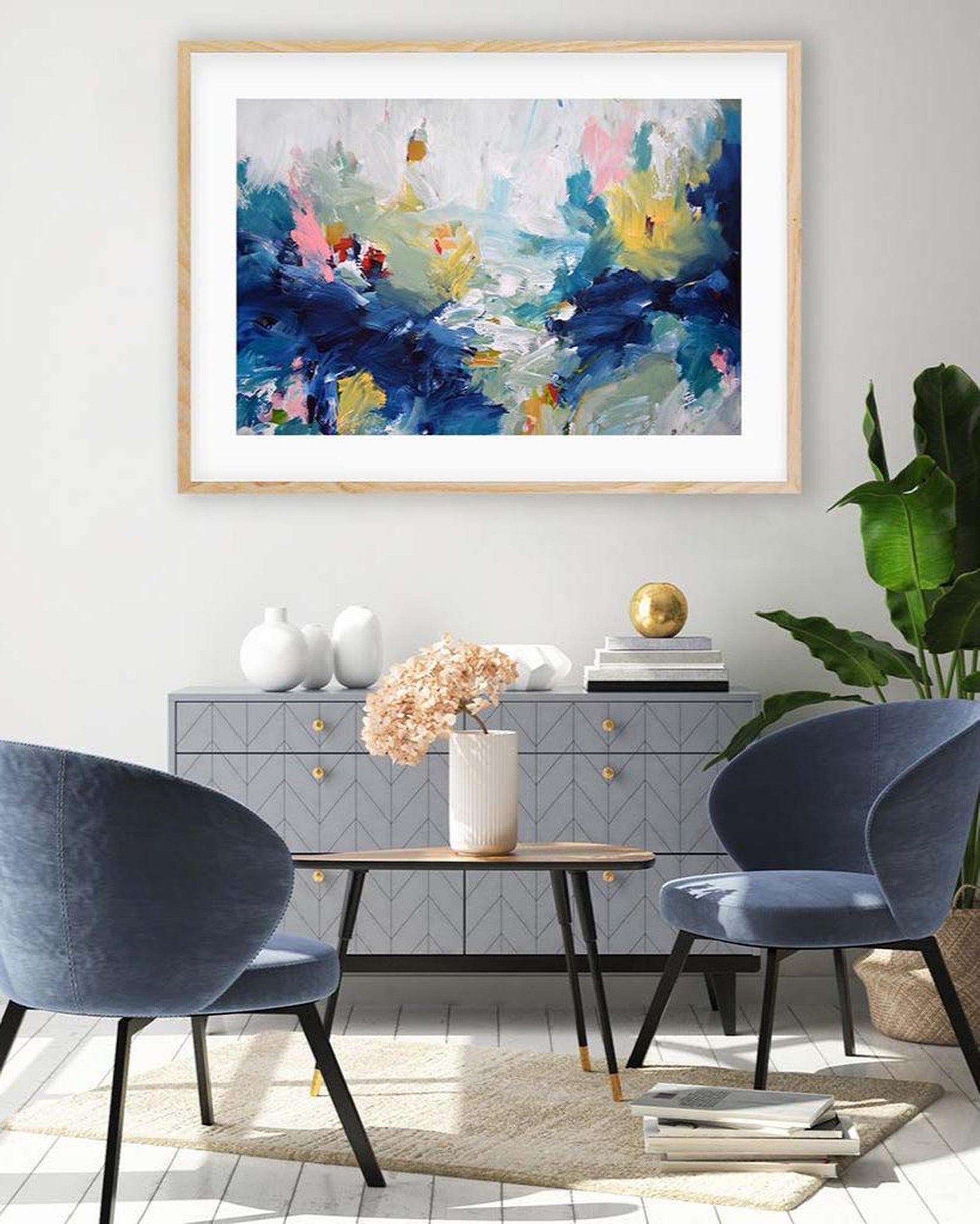 Modern living room with abstract art, blue chairs, and a side table.