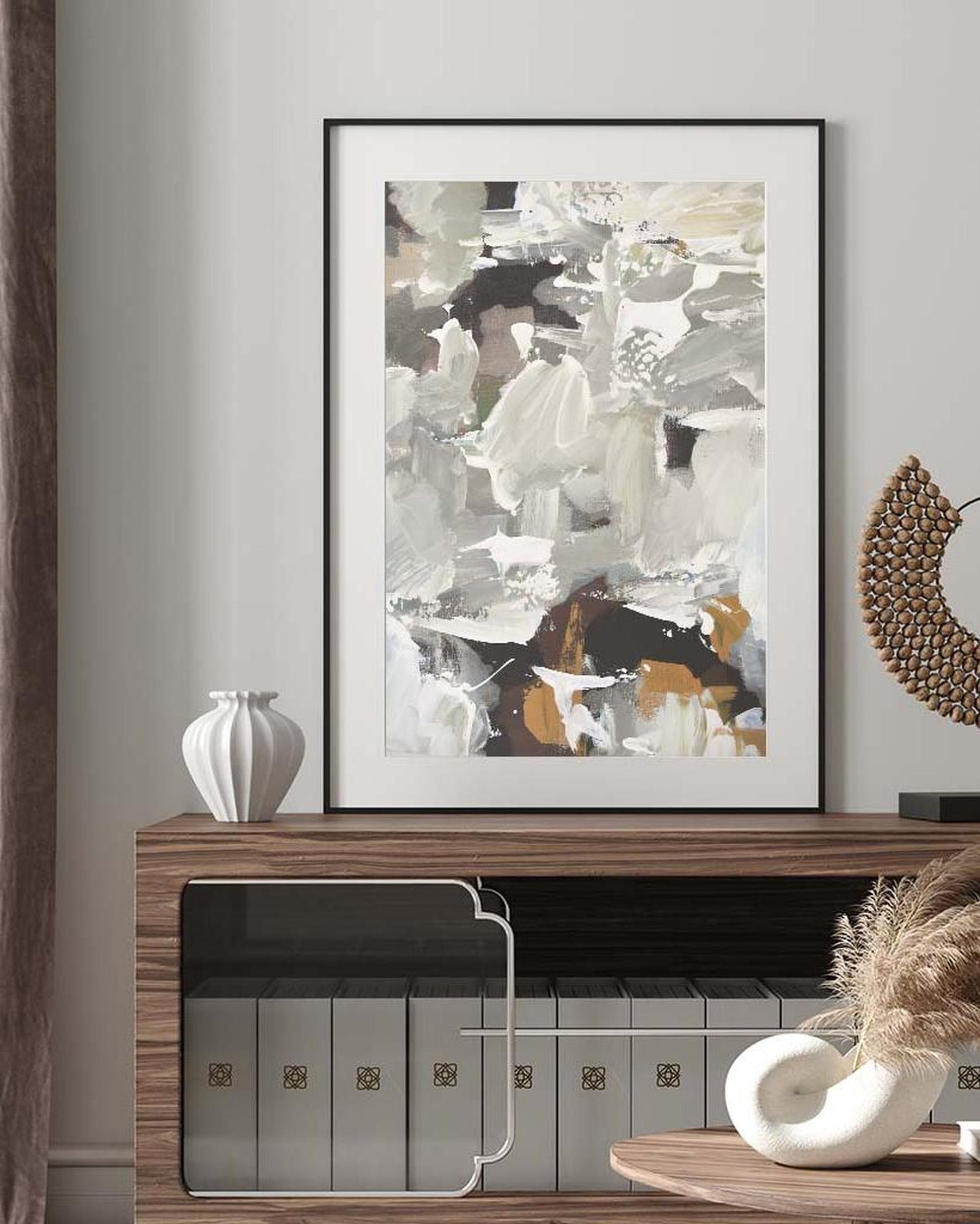 Framed abstract art on a wall above a wooden shelf with decorative items.