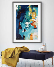 Abstract art print on a wall above a bench with a yellow blanket