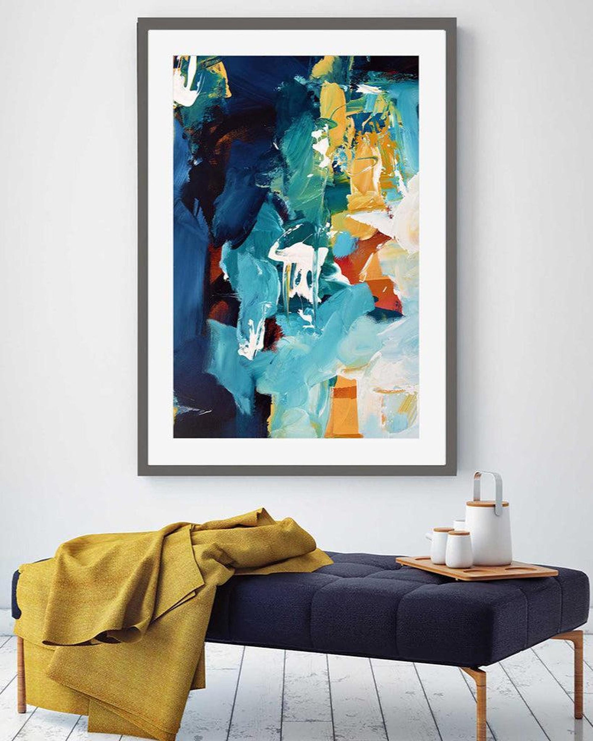 Abstract art print on a wall above a bench with a yellow blanket