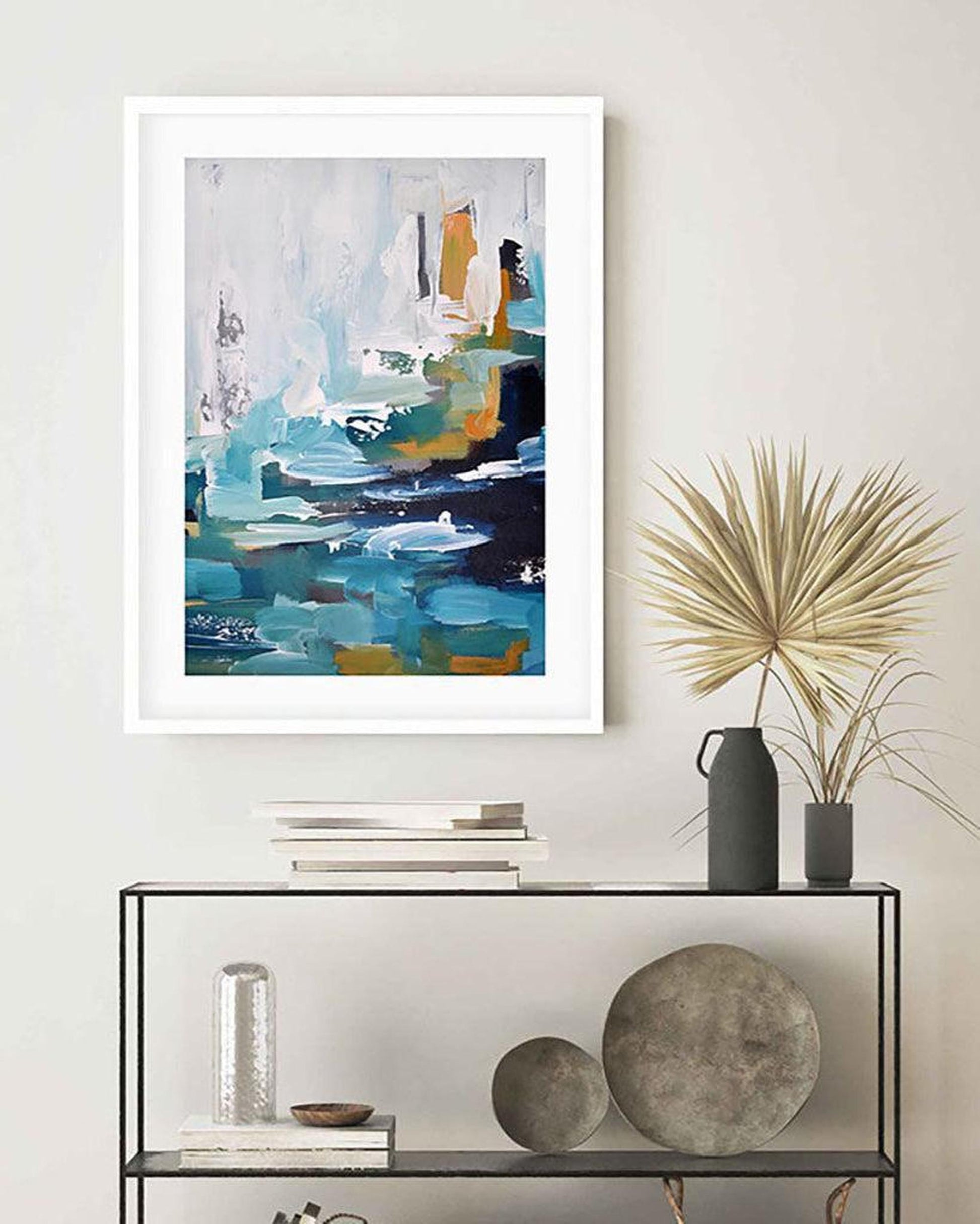 Framed abstract art piece on a wall above a console table with decorative items.