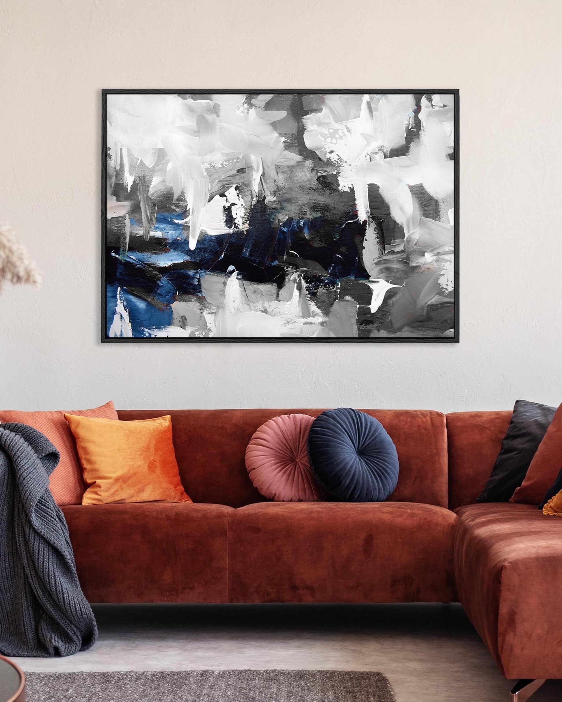 Living room with a brown sofa, colorful cushions, and an abstract painting on the wall.