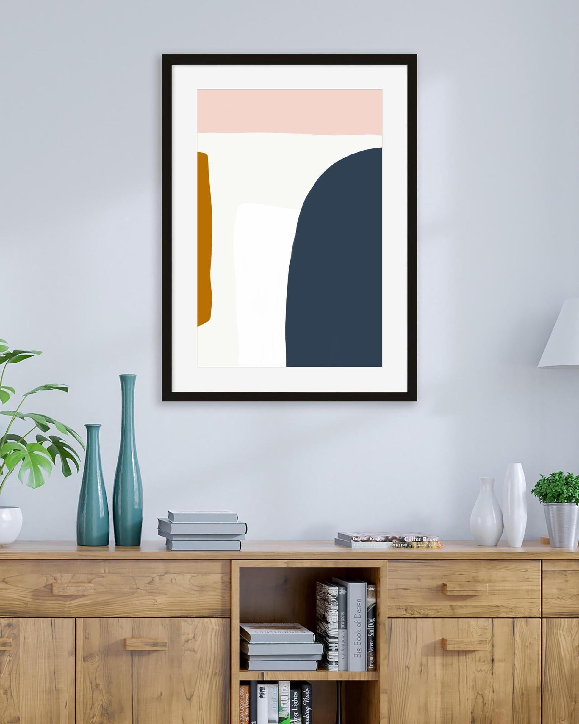 Abstract art print on a wall above a wooden cabinet with decorative items.