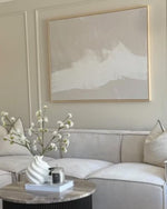 A large beige neutral wall art above a modern sofa in a styled living room