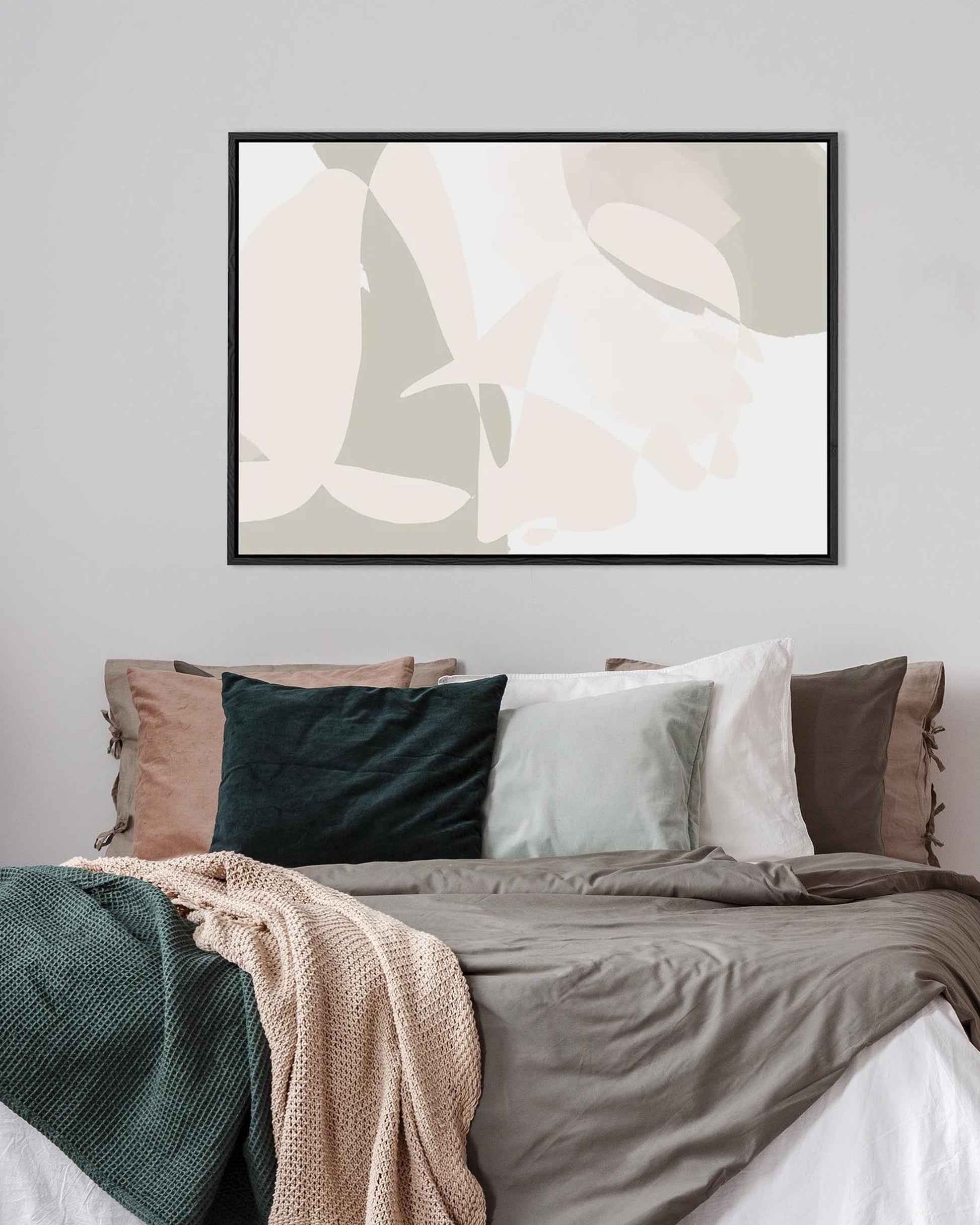 Bedroom with abstract art on the wall, pillows, and a blanket.