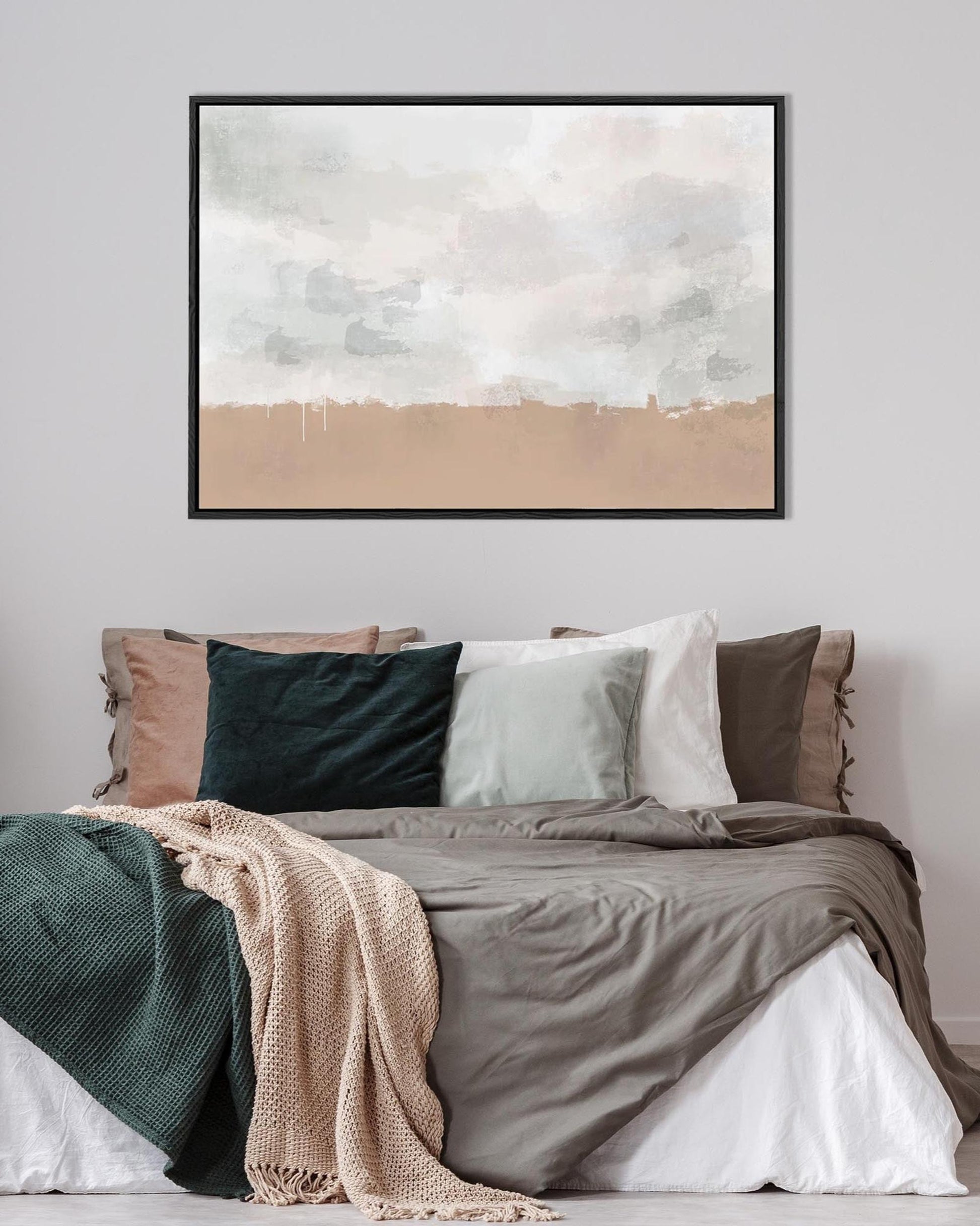 Bedroom with a bed featuring green, beige, and brown bedding, a lamp on a nightstand, and abstract art on the wall.