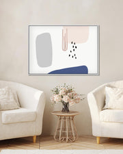 Abstract art piece on a wall above a side table with flowers in a living room.