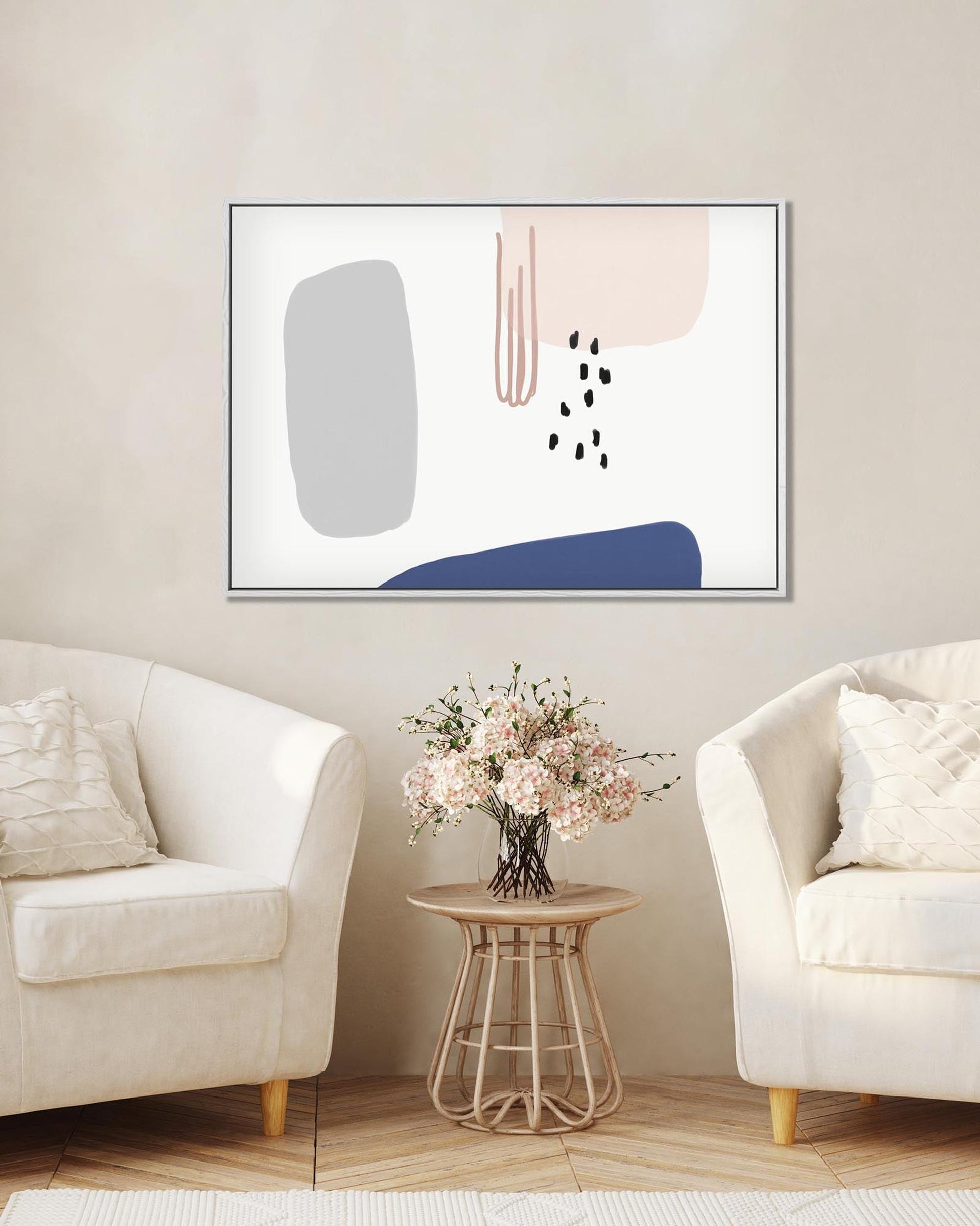 Abstract art piece on a wall above a side table with flowers in a living room.