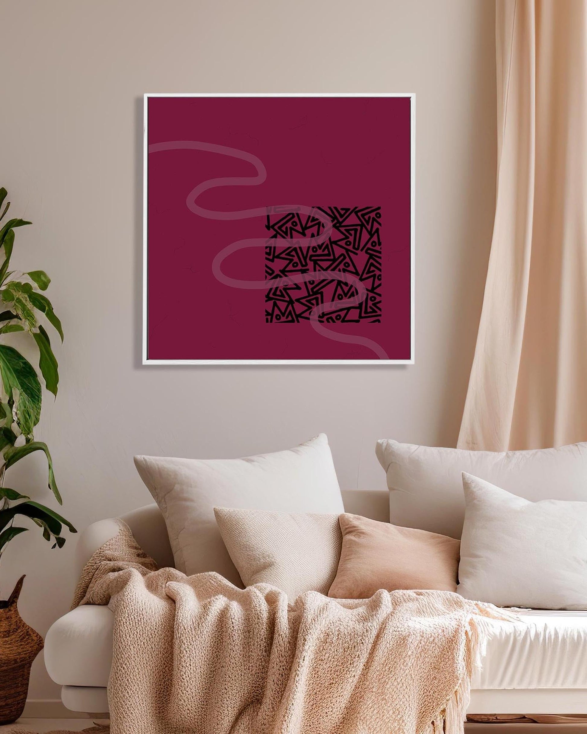 Framed abstract art on a wall above a sofa with a plant to the left.