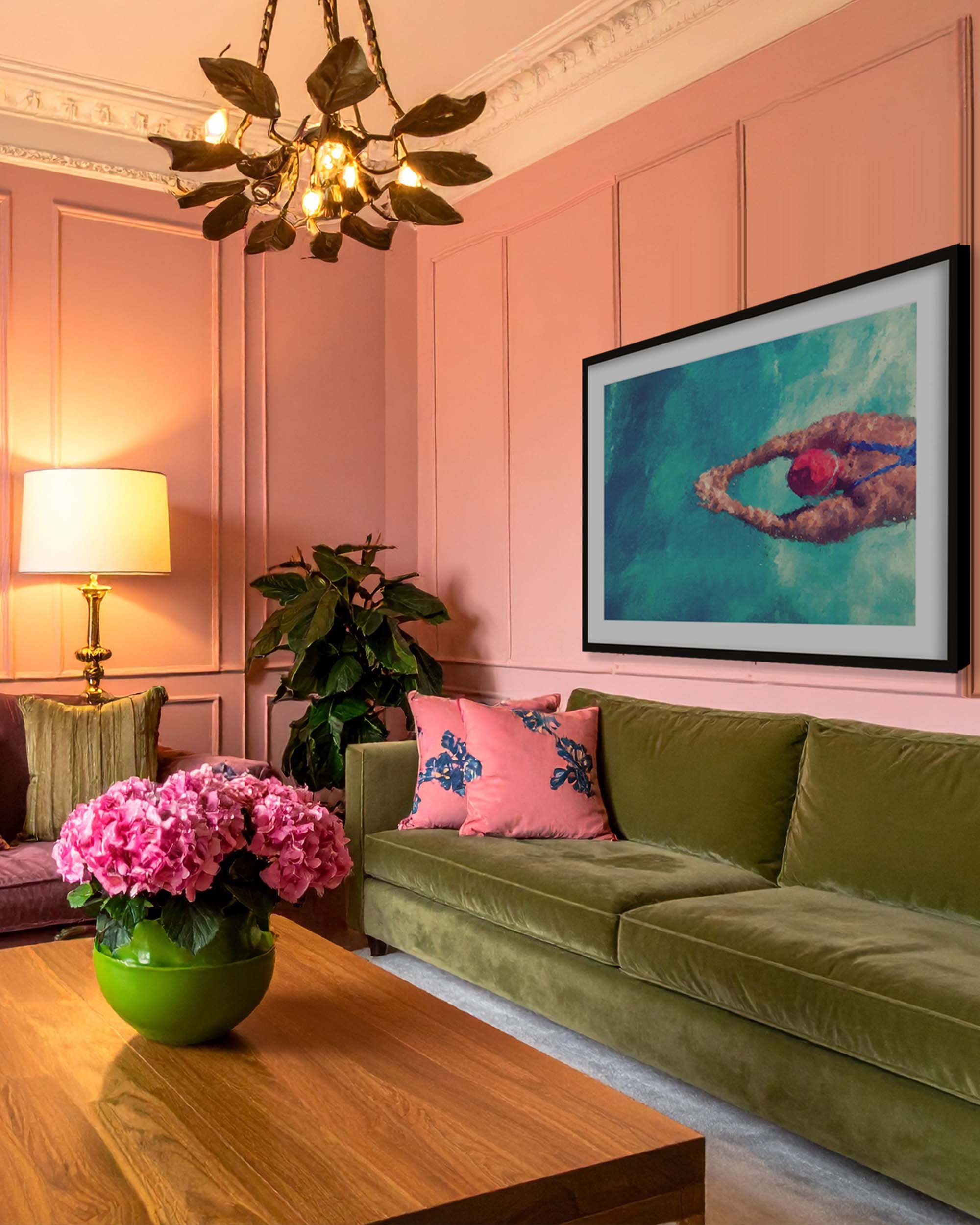 Living room with pink walls, green sofa, and decorative elements, featuring large portrait and figurative framed wall art print of swimmer.