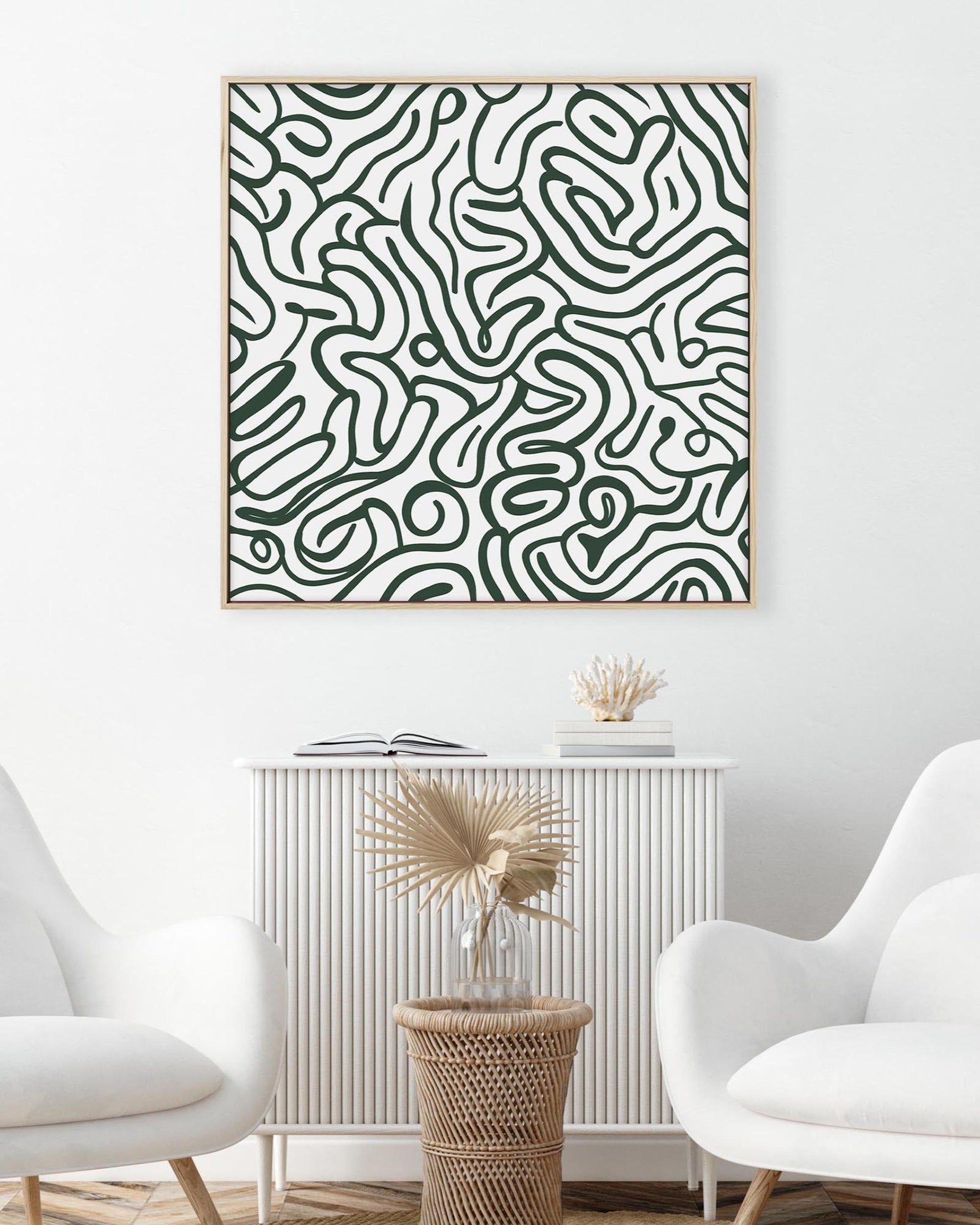 Abstract black and white patterned artwork on a wall above a white cabinet with decorative items.