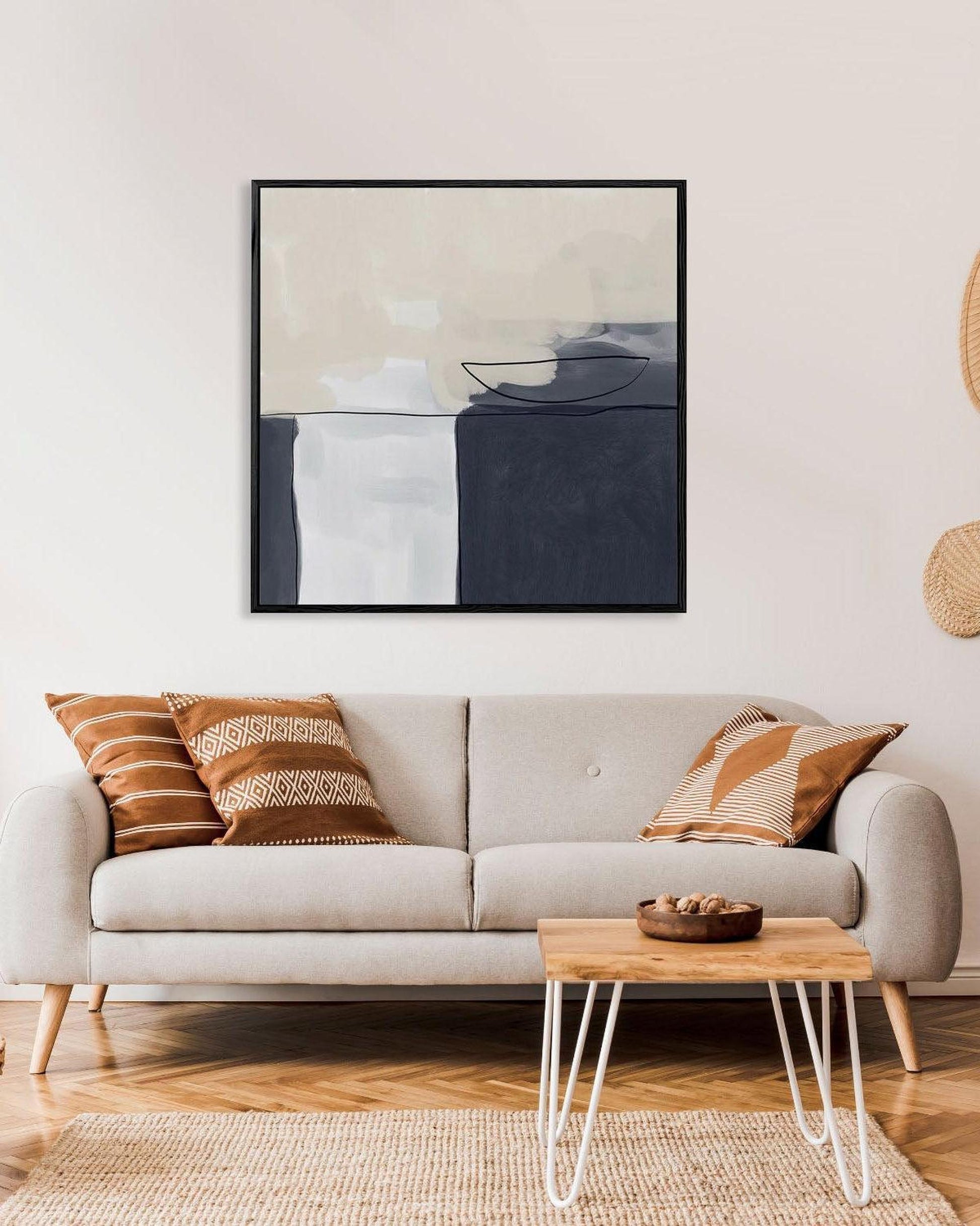 Modern living room with a beige sofa, abstract art, and wooden coffee table.