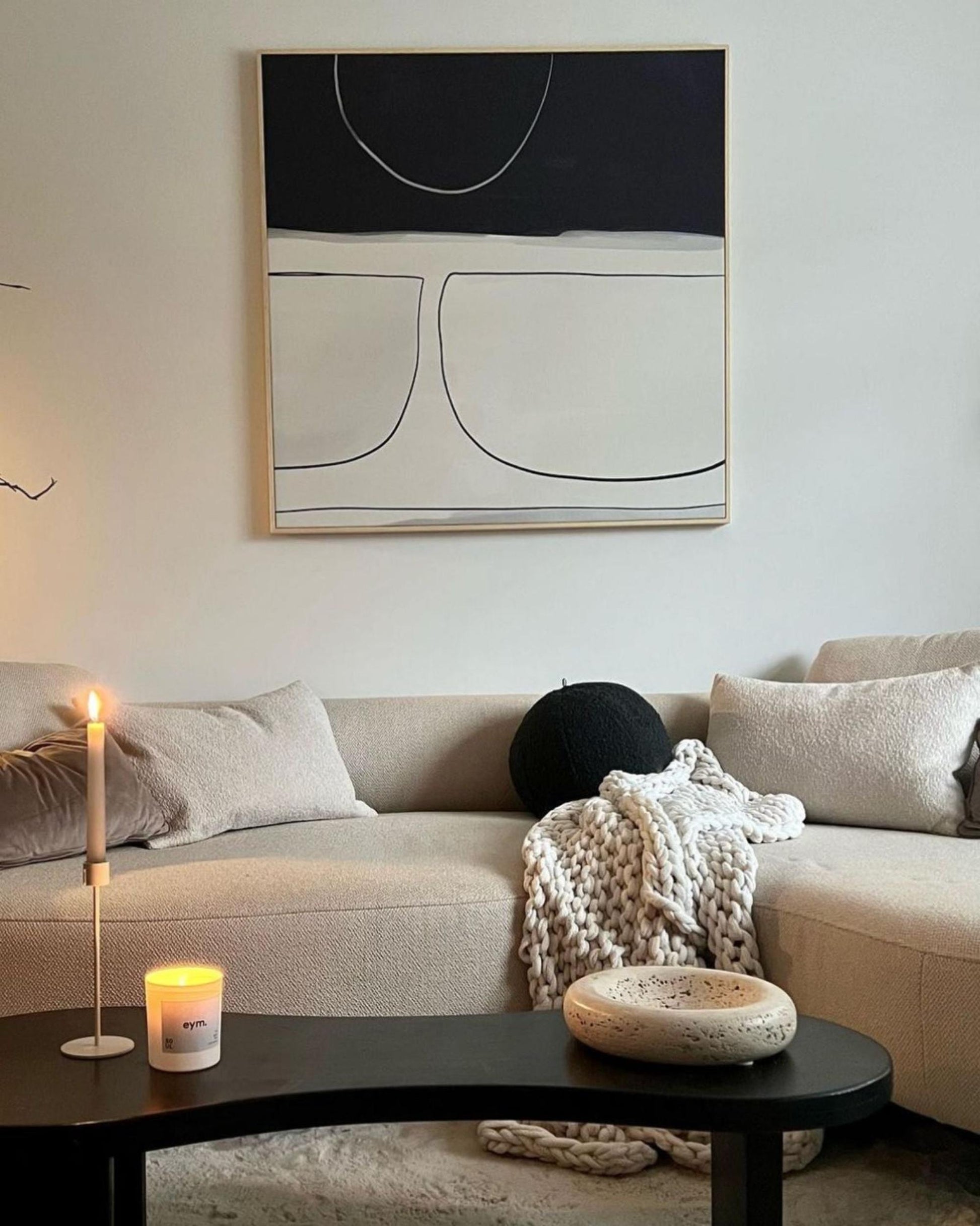 Modern living room with a beige sofa, abstract art, and decorative items.