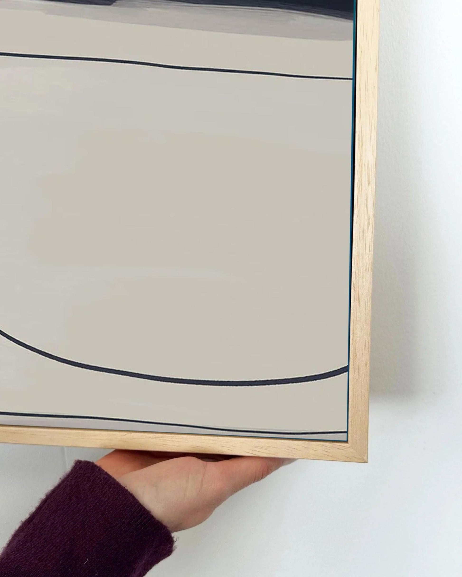Framed abstract art piece held by a hand on a white background