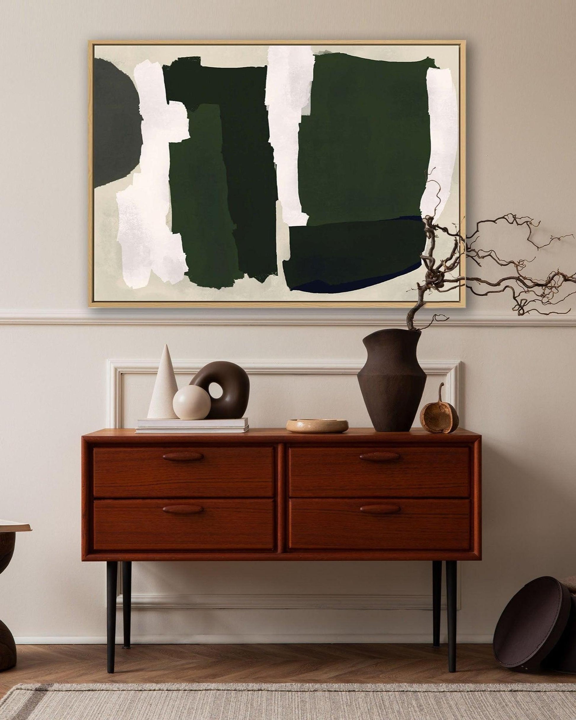 Large abstract picture above mid century wooden vintage sideboard with earthy pots and plants and books and beige large natural rug.