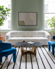 Modern living room with a white sofa, blue chairs, and a marble coffee table.
