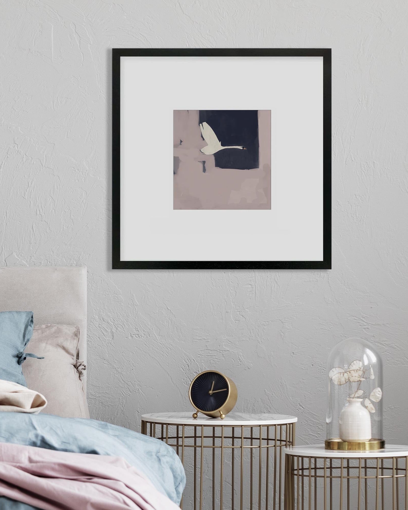 Framed artwork on a wall above a bed with decorative items.