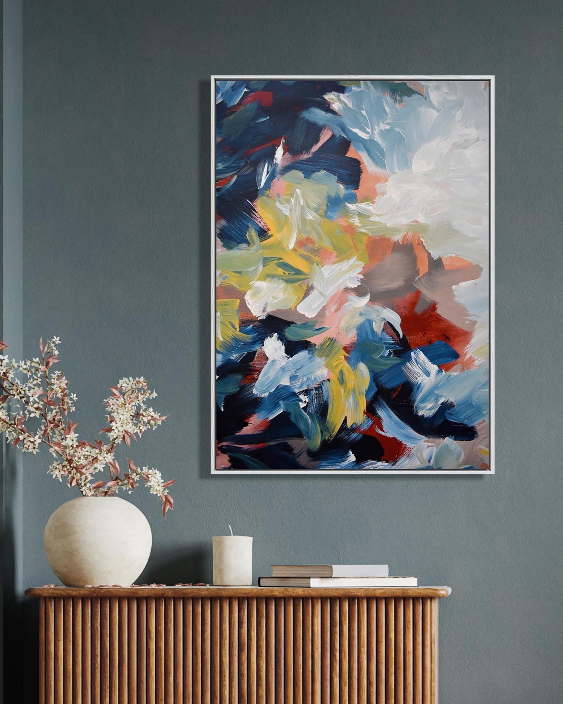 Abstract painting on a wall above a wooden console table with decorative items.