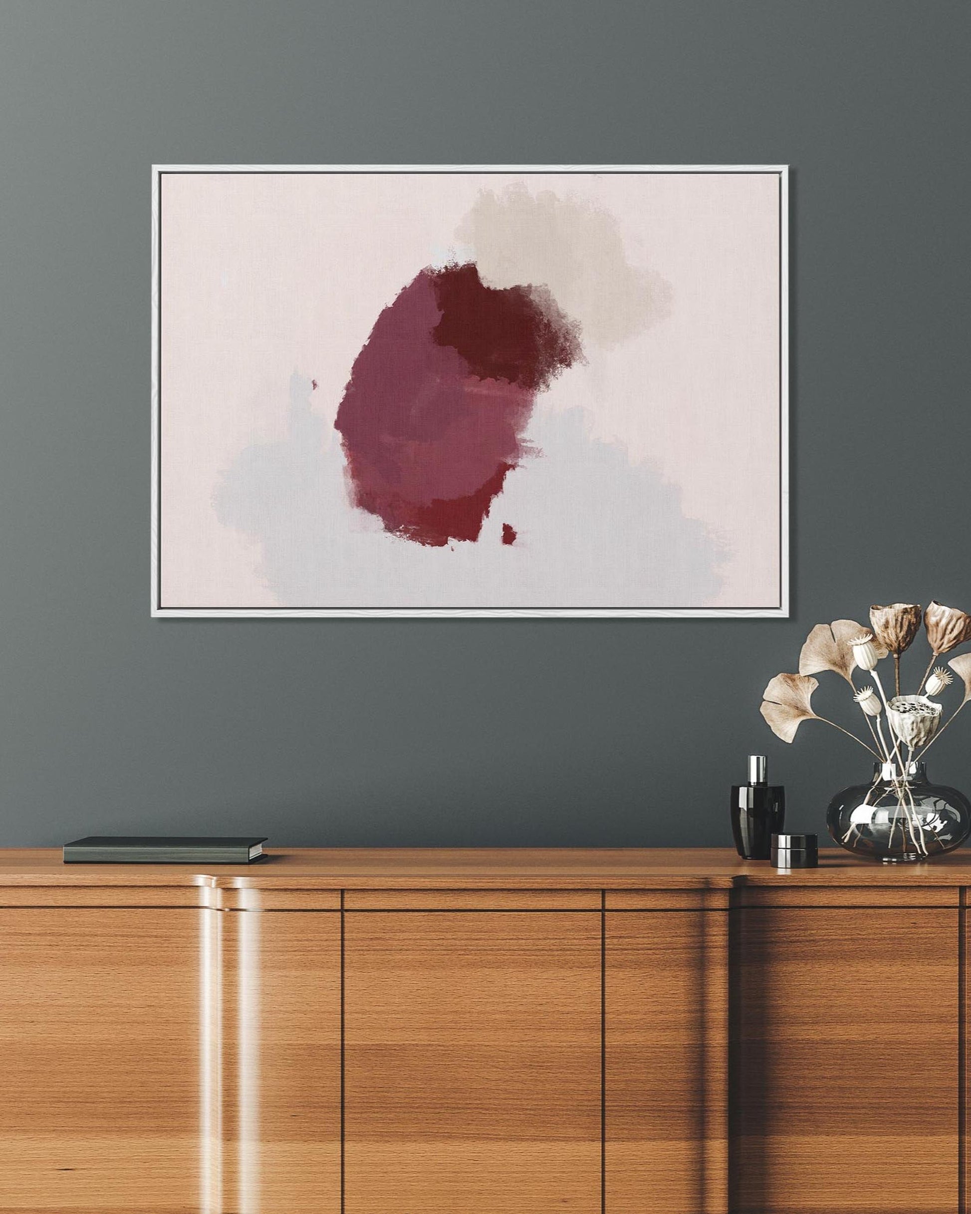 Abstract art piece on a gray wall above a wooden cabinet.