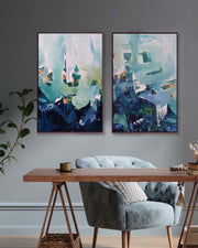 Two abstract paintings above a gray armchair in a room.