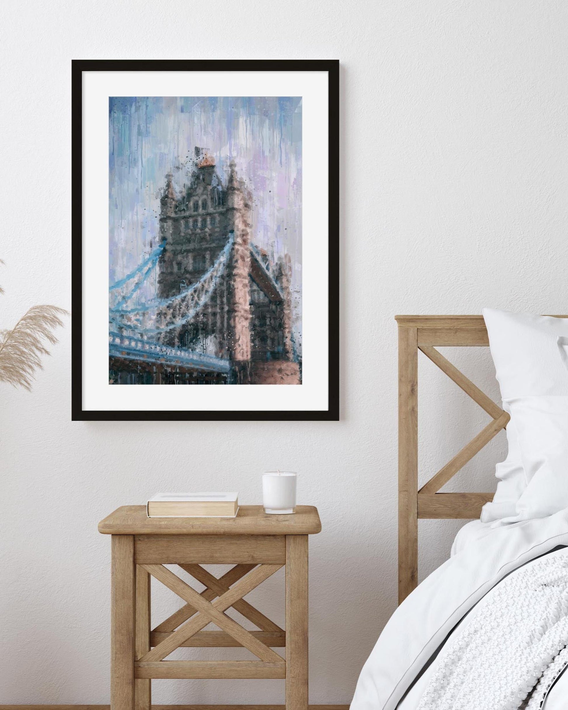 Framed artwork of a bridge on a wall above a wooden side table.
