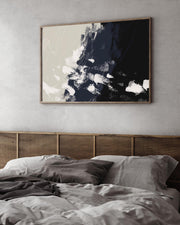 Abstract art piece on a wall above a bed with wicker headboard