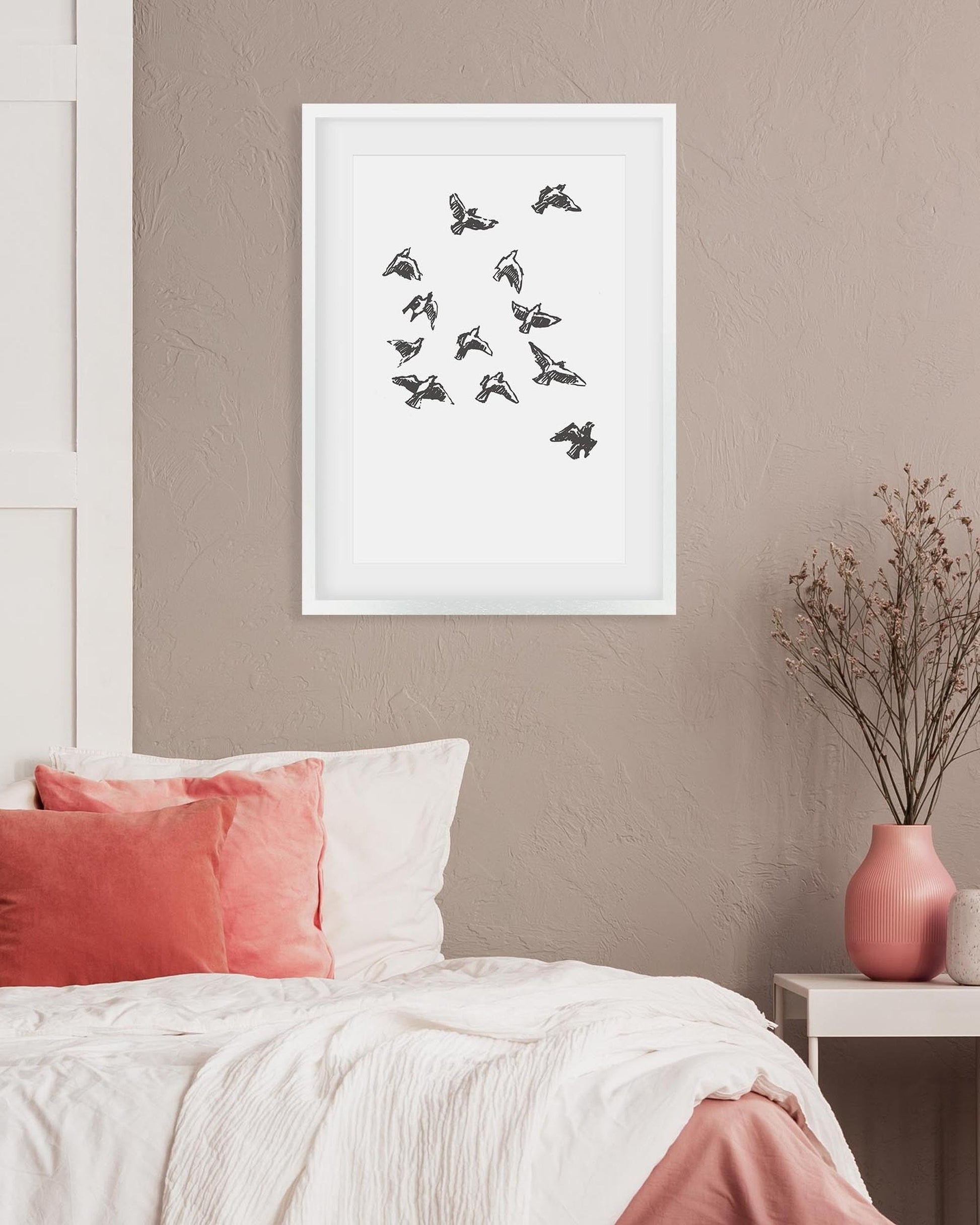 Framed artwork of birds on a wall above a bed with pink and white bedding.