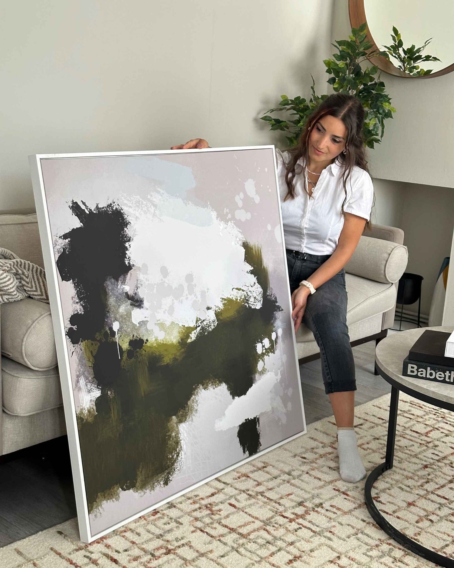 Woman holding a large abstract painting in a living room