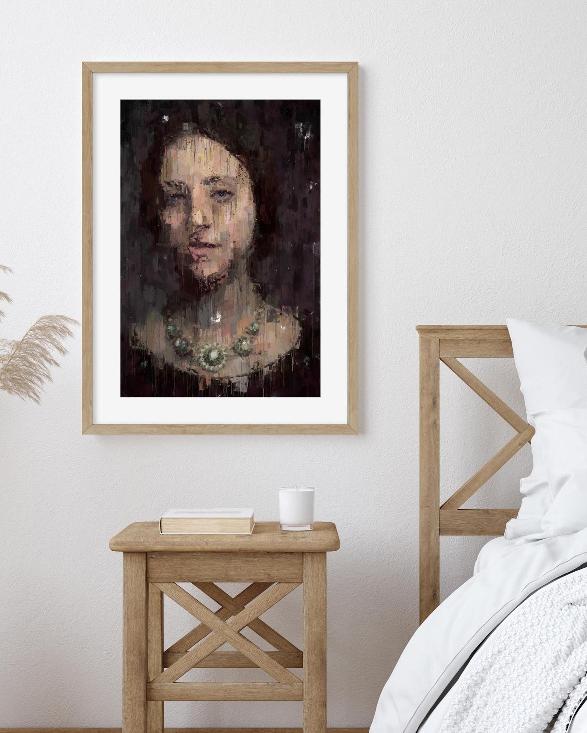 Framed portrait on a wall above a wooden side table in a bedroom setting.