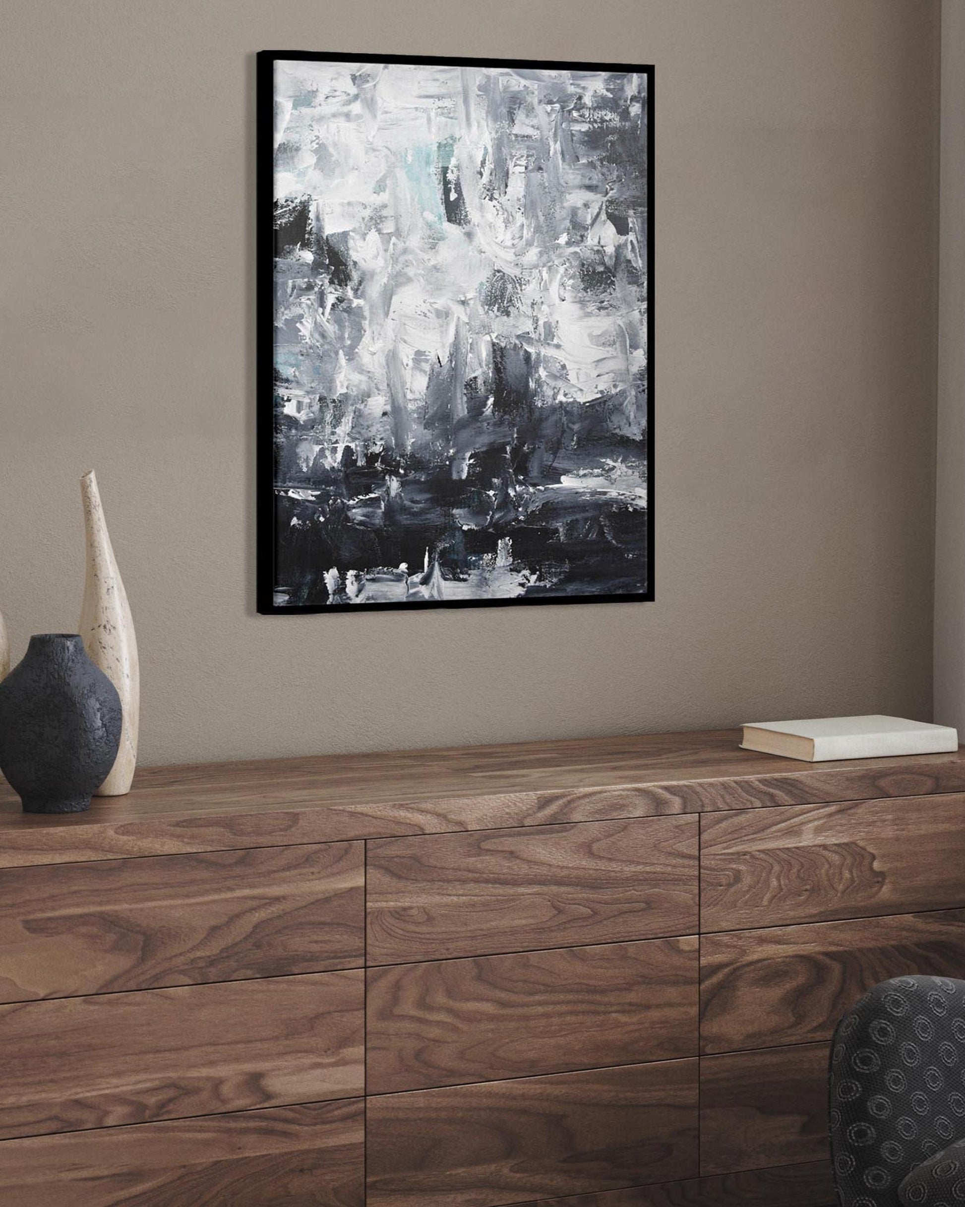 Wooden sideboard with decorative vases and a framed abstract painting on a wall.