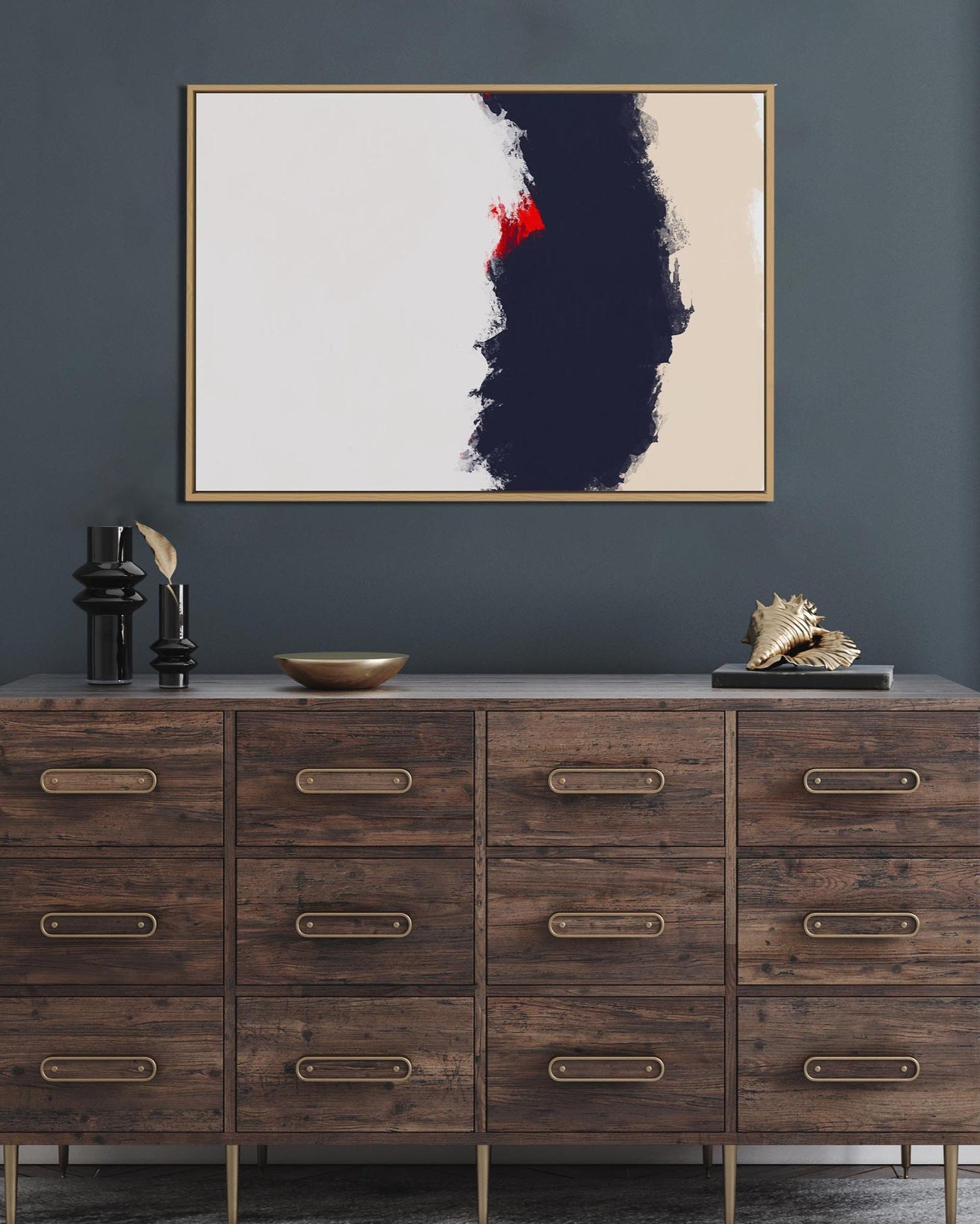 Wooden dresser with decorative items against a dark gray wall with a framed abstract painting.