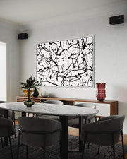 Dining room with a marble table and chairs, abstract black and white painting on the wall, and decorative vases.