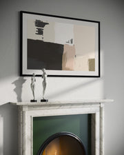 Framed abstract art above a fireplace with decorative sculptures.