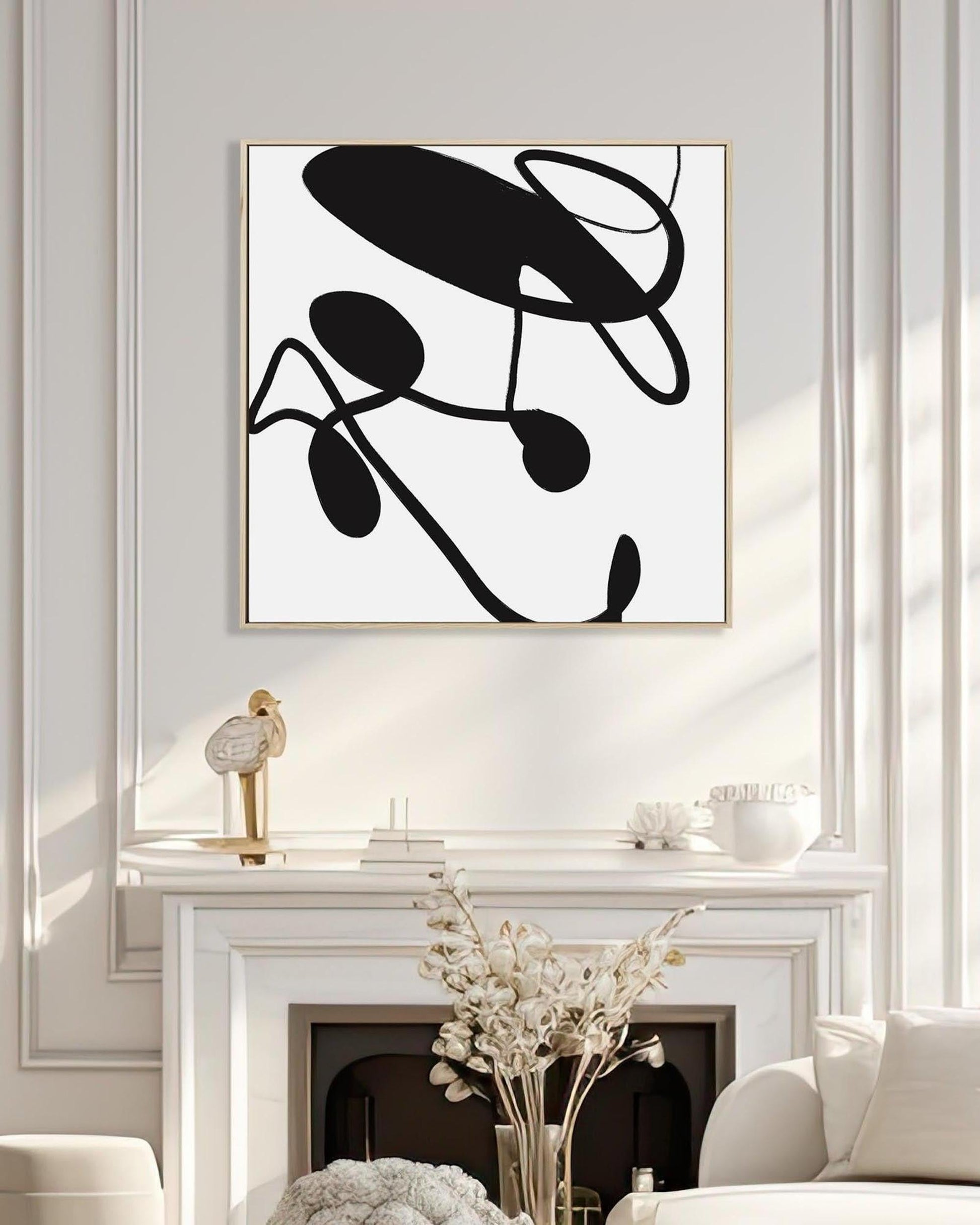 Abstract black and white artwork on a wall above a fireplace.
