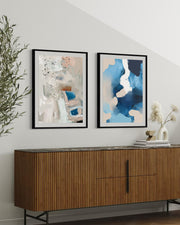 Two framed abstract paintings above a wooden sideboard with decorative items.