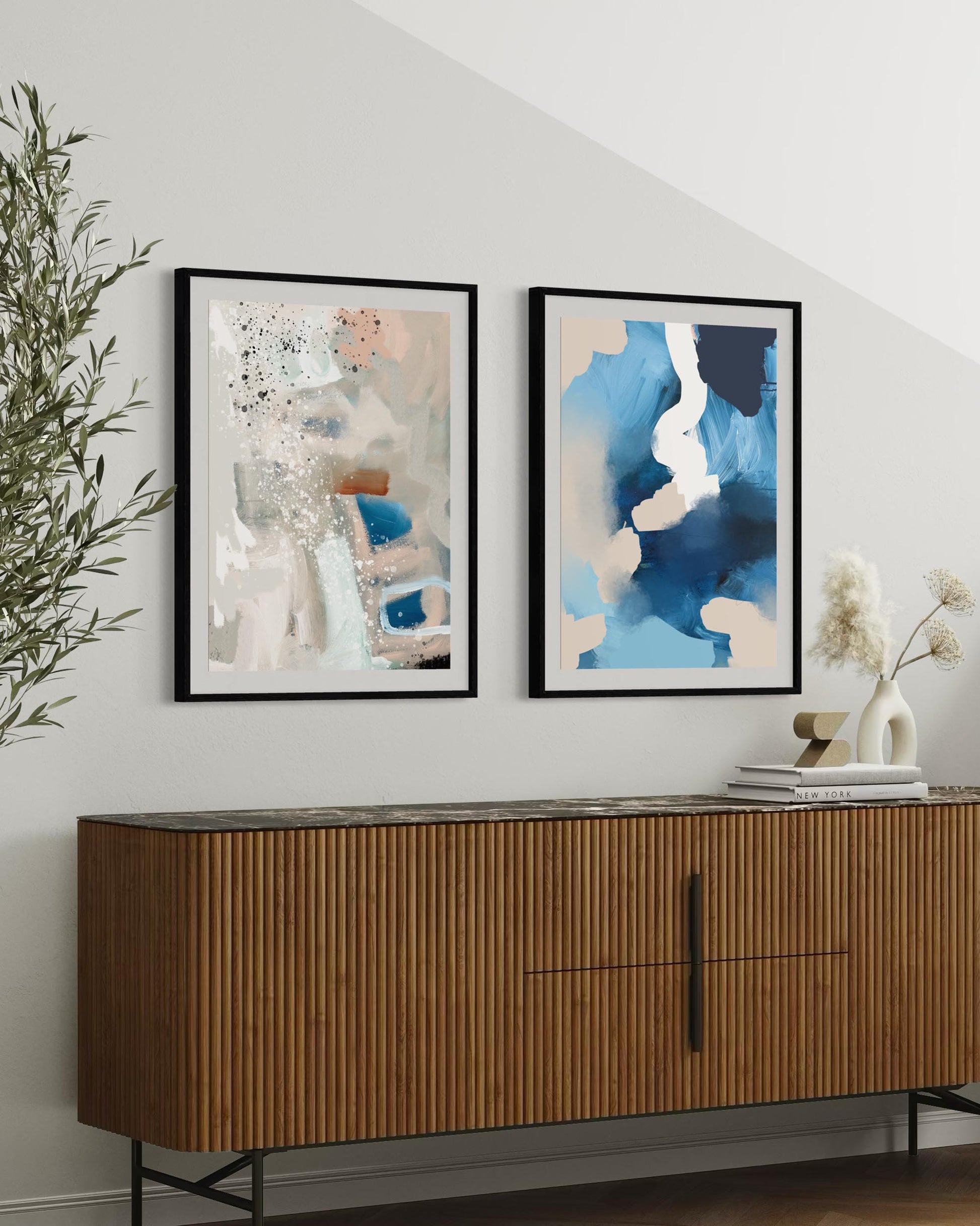 Two framed abstract paintings above a wooden sideboard with decorative items.