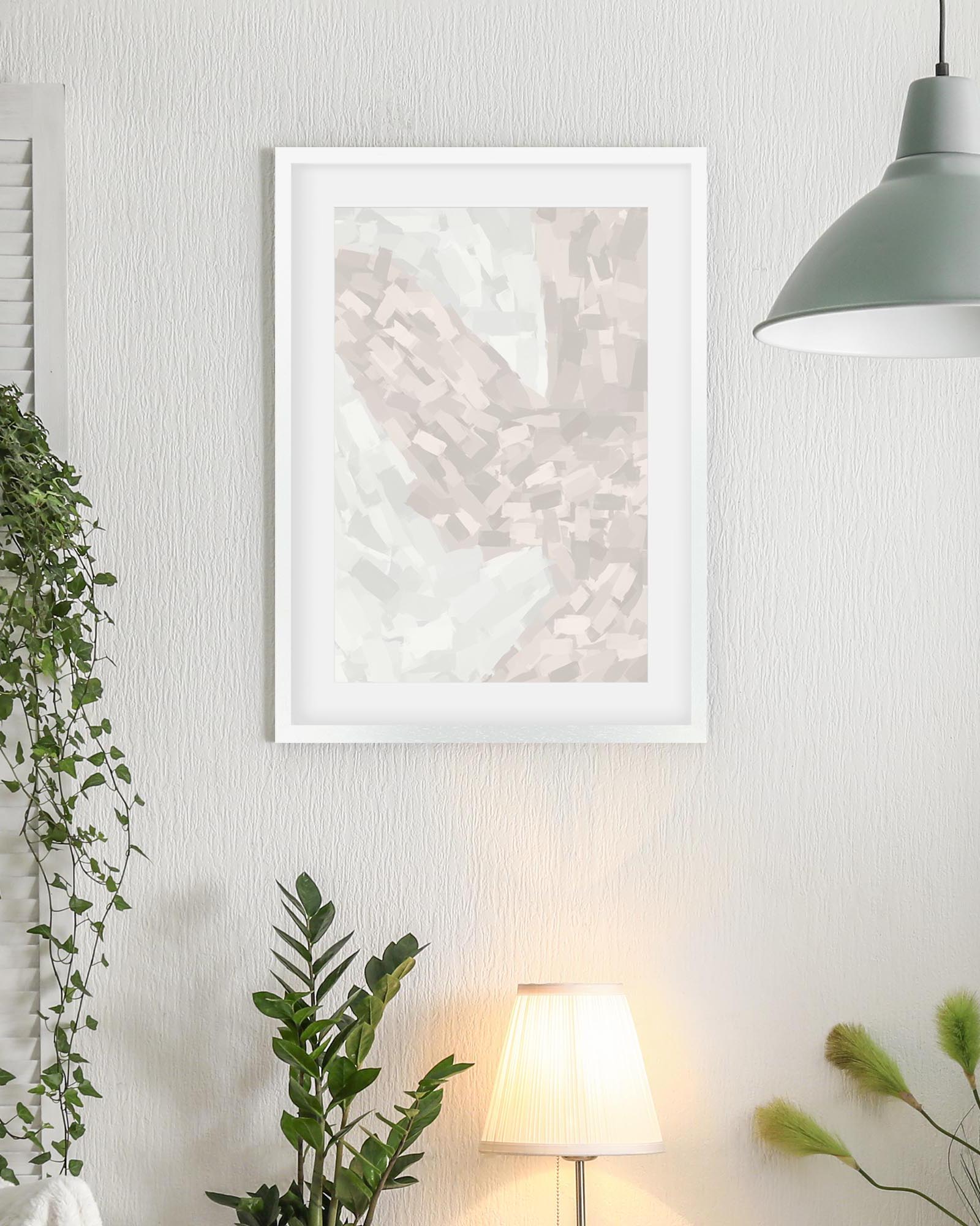 Framed abstract art print on a wall with plants and a lamp in the background