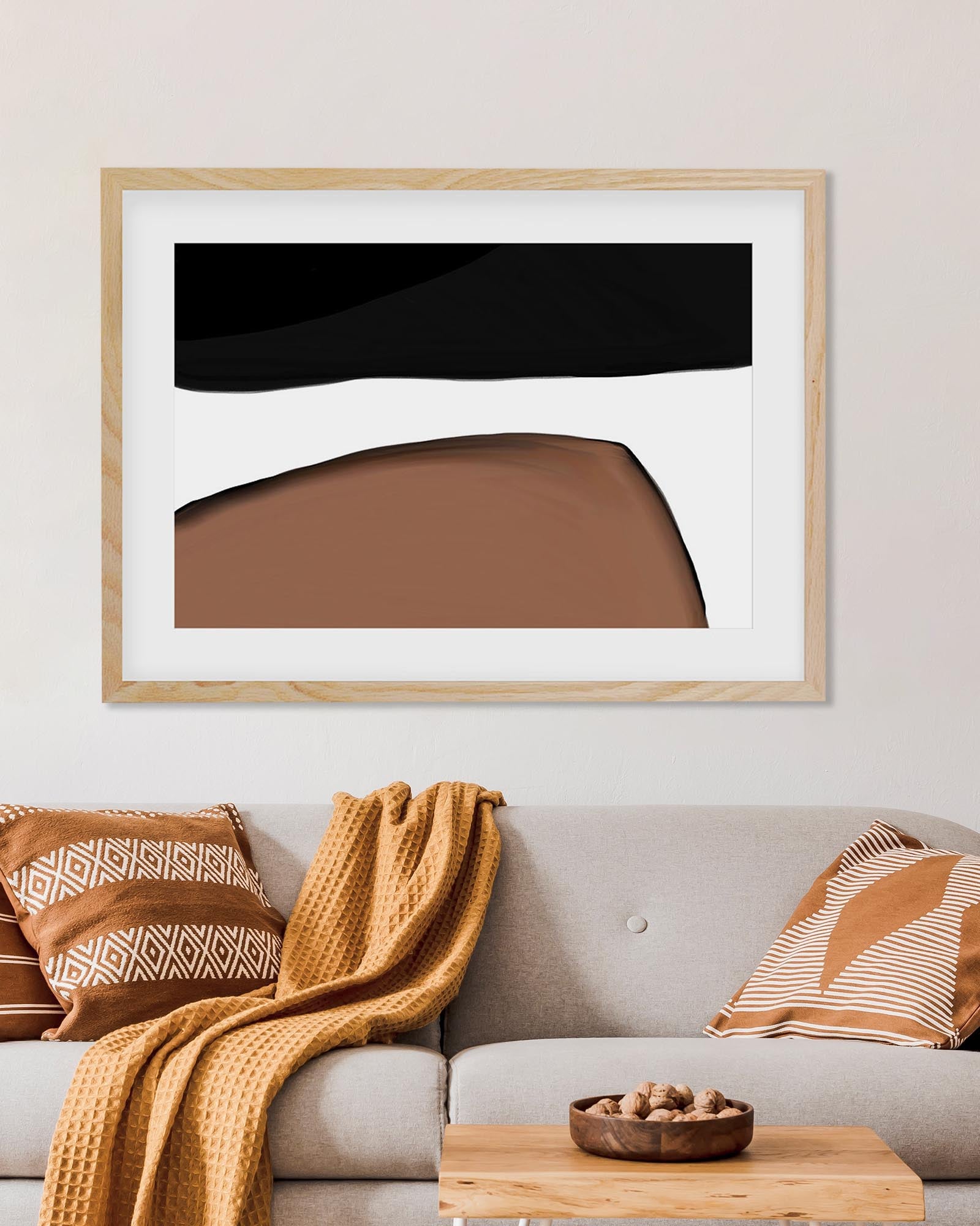 Framed abstract art piece on a wall above a sofa with decorative pillows and a blanket.