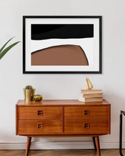 Wooden dresser with abstract art above it on a white wall
