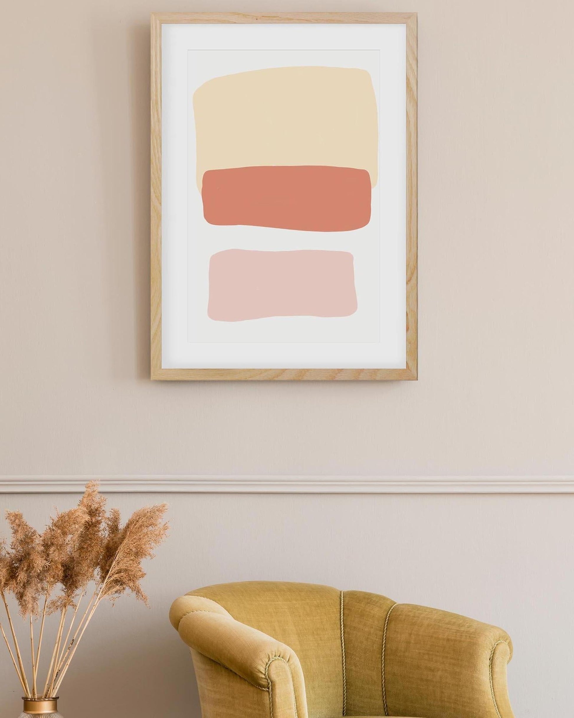 Framed abstract art with geometric shapes on a wall above a yellow armchair.