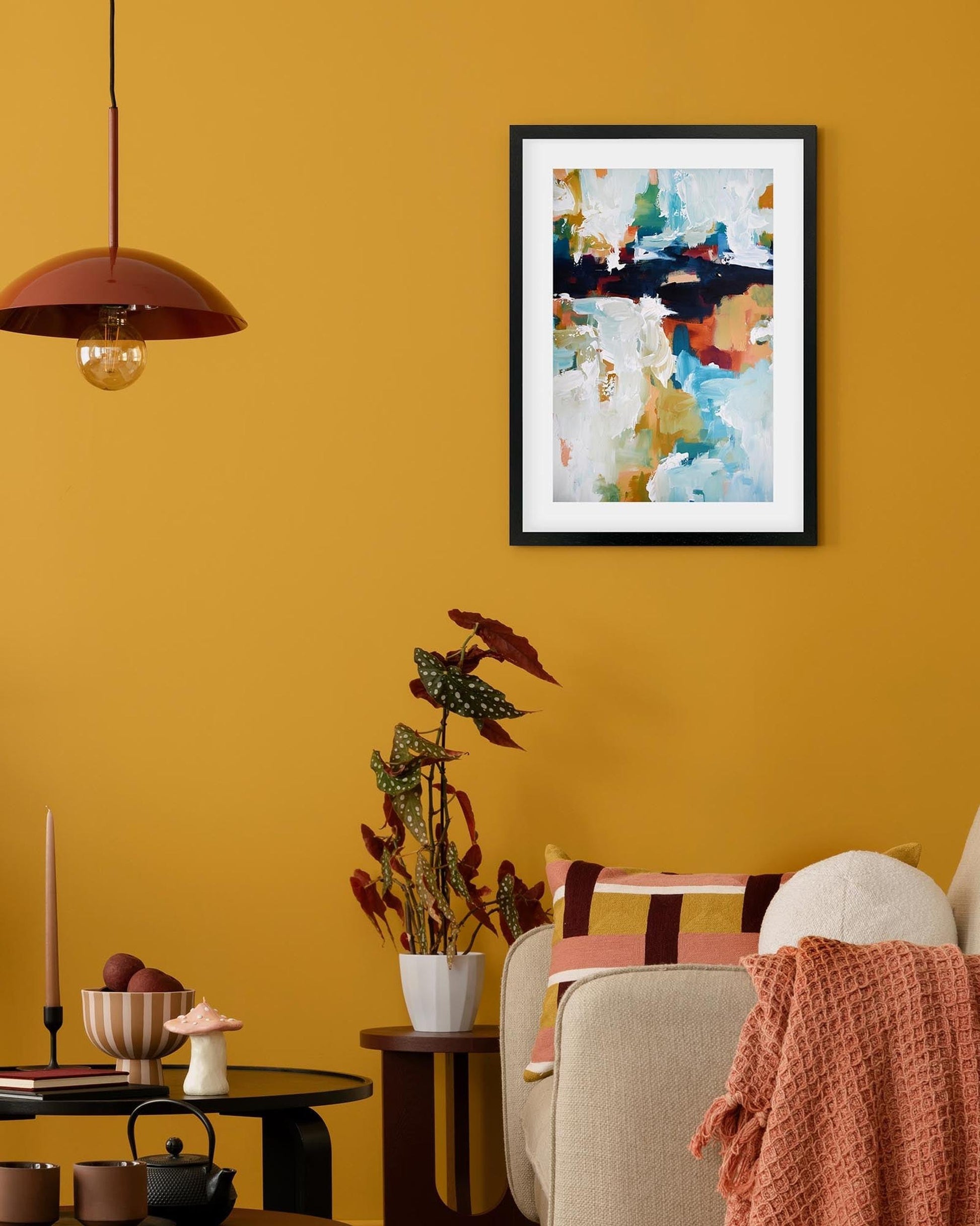 Living room with yellow walls, a framed abstract painting, and decorative items.