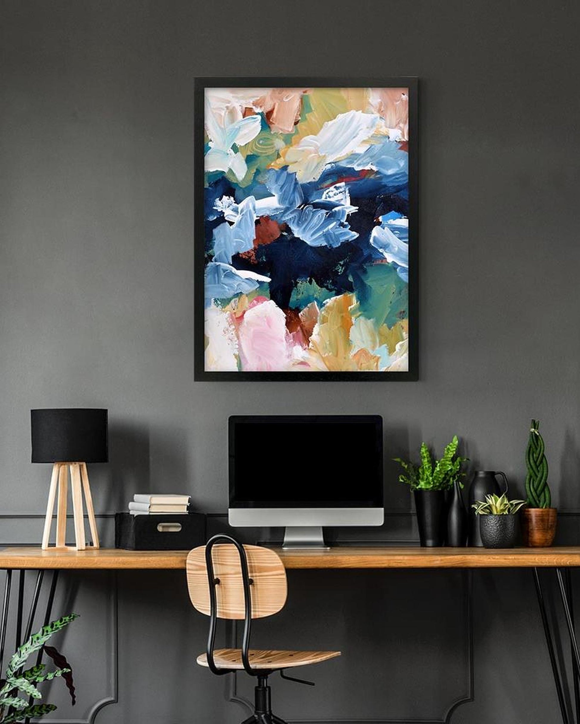 Modern office setup with a colorful abstract painting on a gray wall.