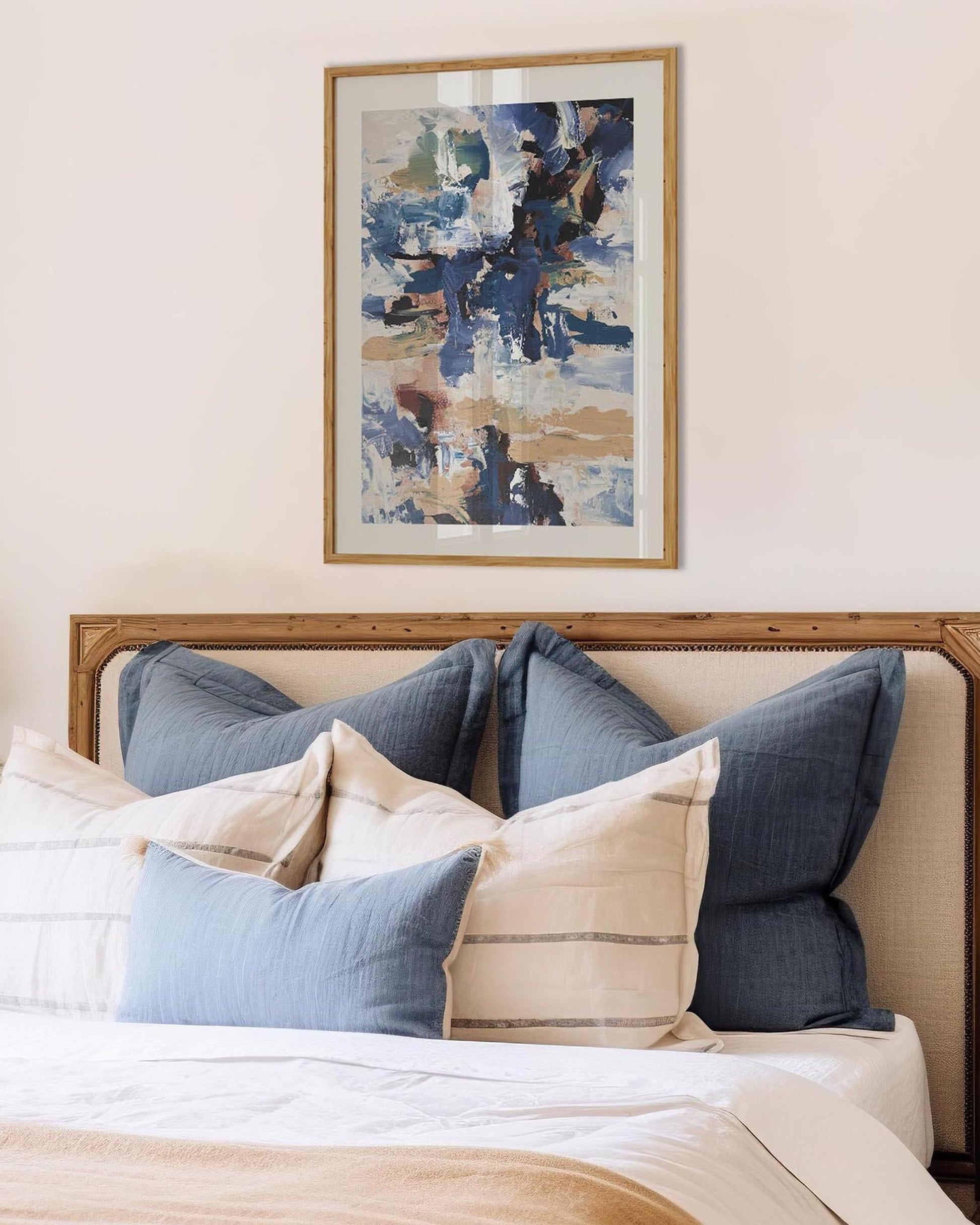 Bedroom with a bed featuring blue and beige pillows, and abstract art on the wall.