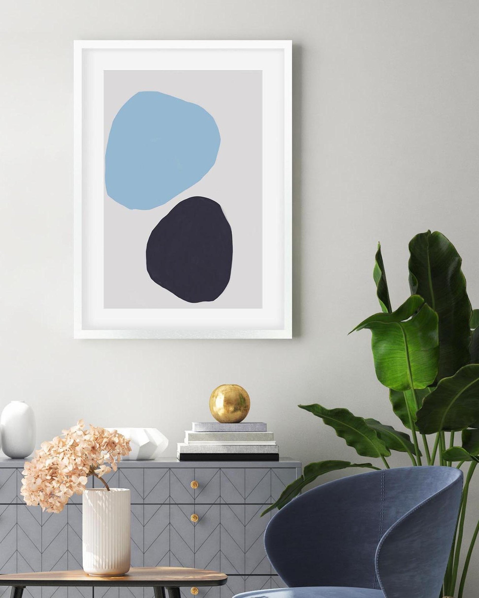 Framed abstract art with blue and black shapes on a wall in a living room.