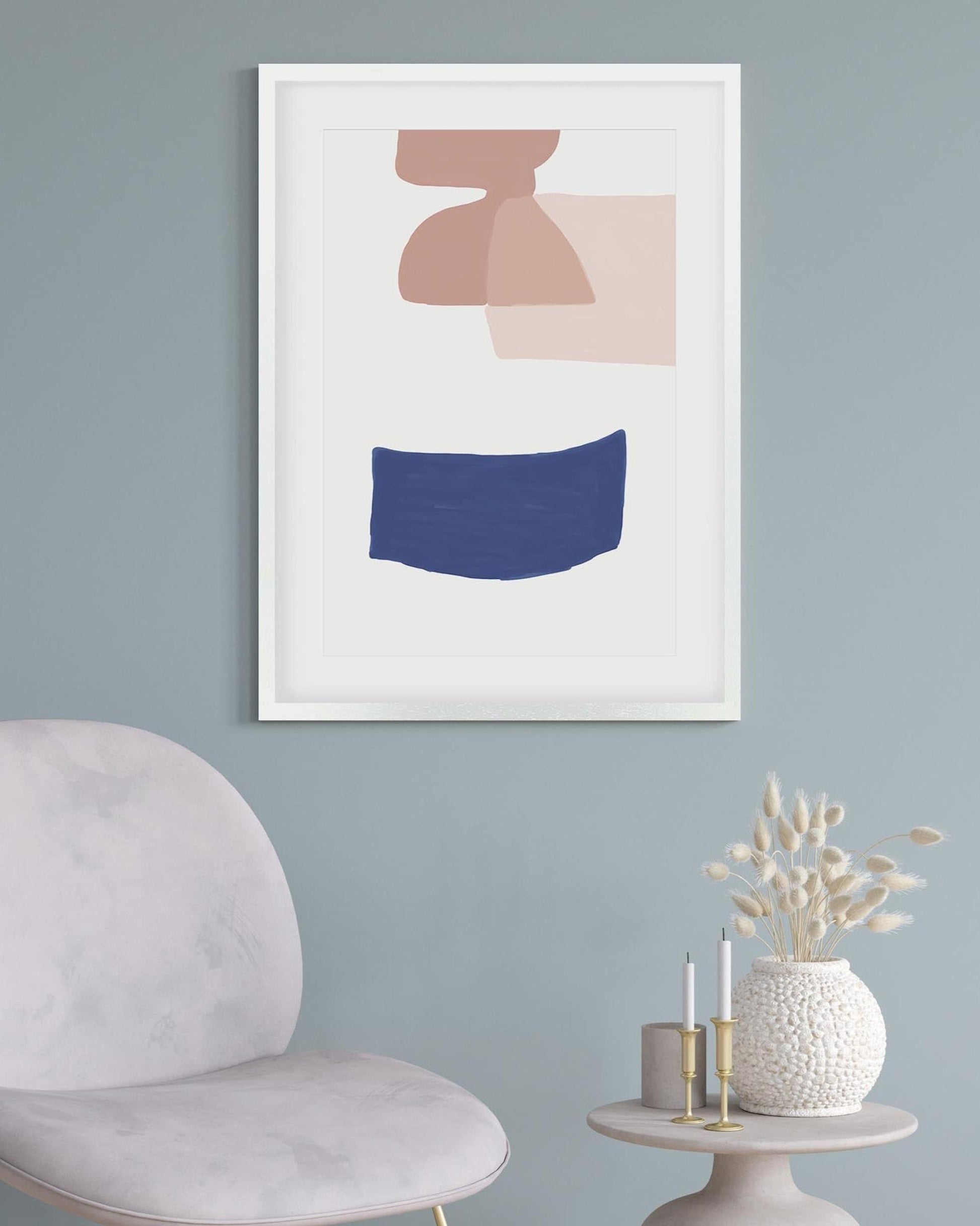Framed abstract art print on a wall with a chair and small table in the foreground.