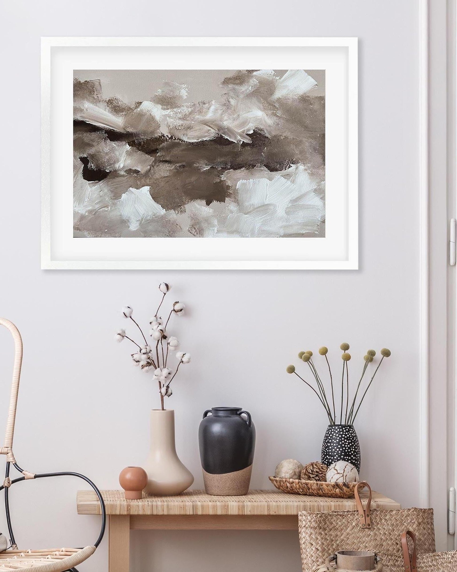 Framed abstract art above a wooden console table with decorative items.