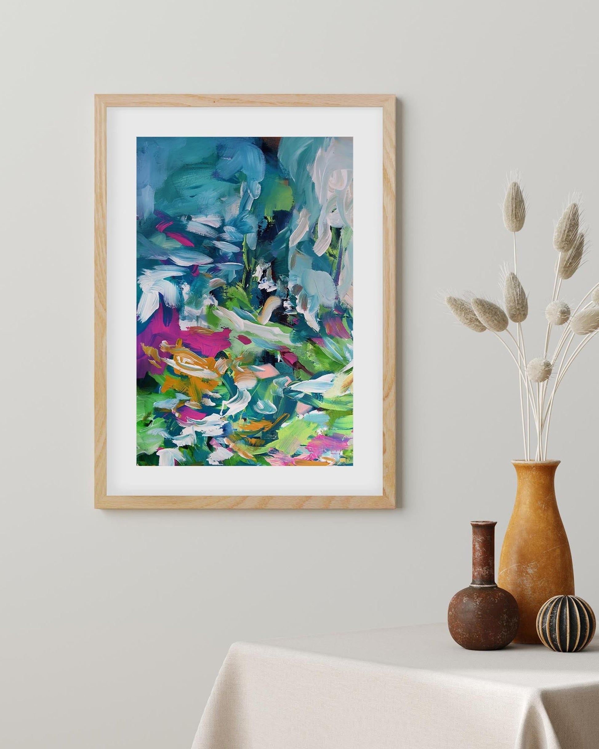Framed abstract artwork on a wall with decorative vases below.